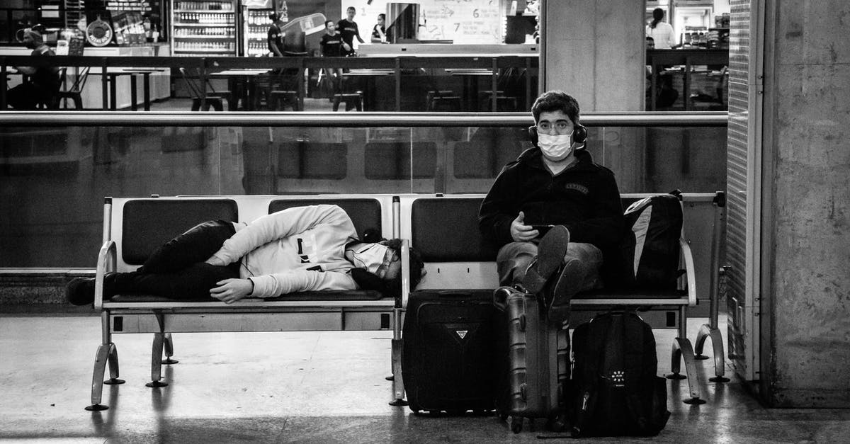 Sleep/stay at the Stuttgart airport without a visa - Anonymous tourists in masks on bench in airport