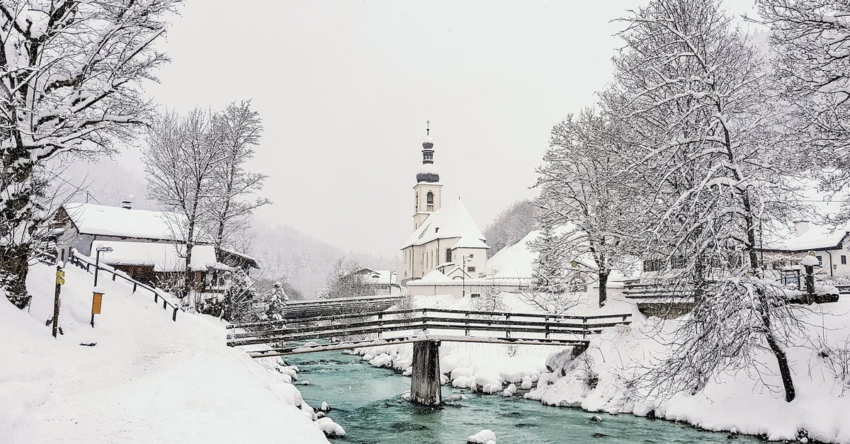 Small historical stone bridge in the North of Seoul - Aged bridge above narrow river with stones between snowy trees and temple exterior on hill in town