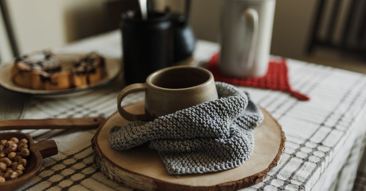 Small, warm towel on an airplane - what is it for? - Ceramic Mug in Knitted Towel on Brown Wooden Coaster