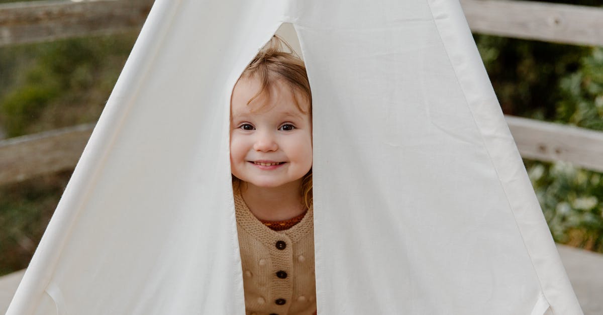 Small, warm towel on an airplane - what is it for? - Happy little child smiling while peeking from tent