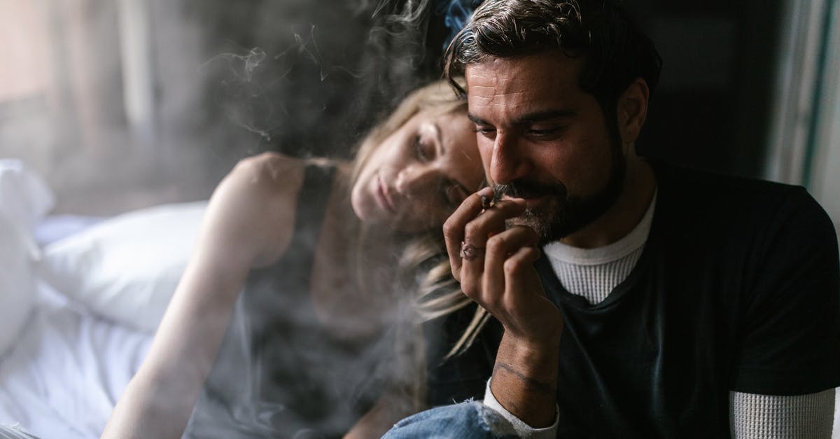 Smoking weed in Amsterdam as a tourist - Man in Blue Denim Jacket Smoking Cigarette