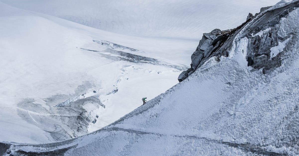 Snowshoeing/hiking in December in Geneva - From above distant alpinist on snowy rough mountain slope against frozen spacious mountainous valley in daylight