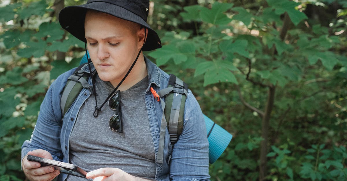 Social Travel App for managing Itinerary - Serious young man using tablet in forest during hiking tour