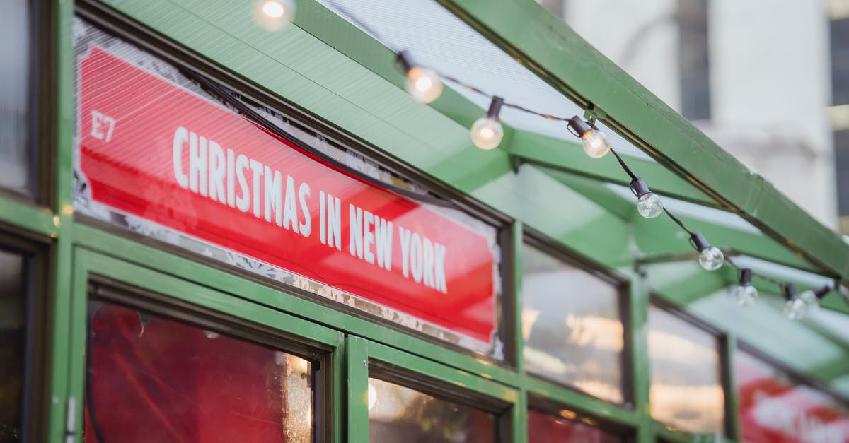 Solo-Driving from Florida to New York During the Winter - Low angle red signboard with Christmas In New York inscription hanging on glass showcase of shop on city street