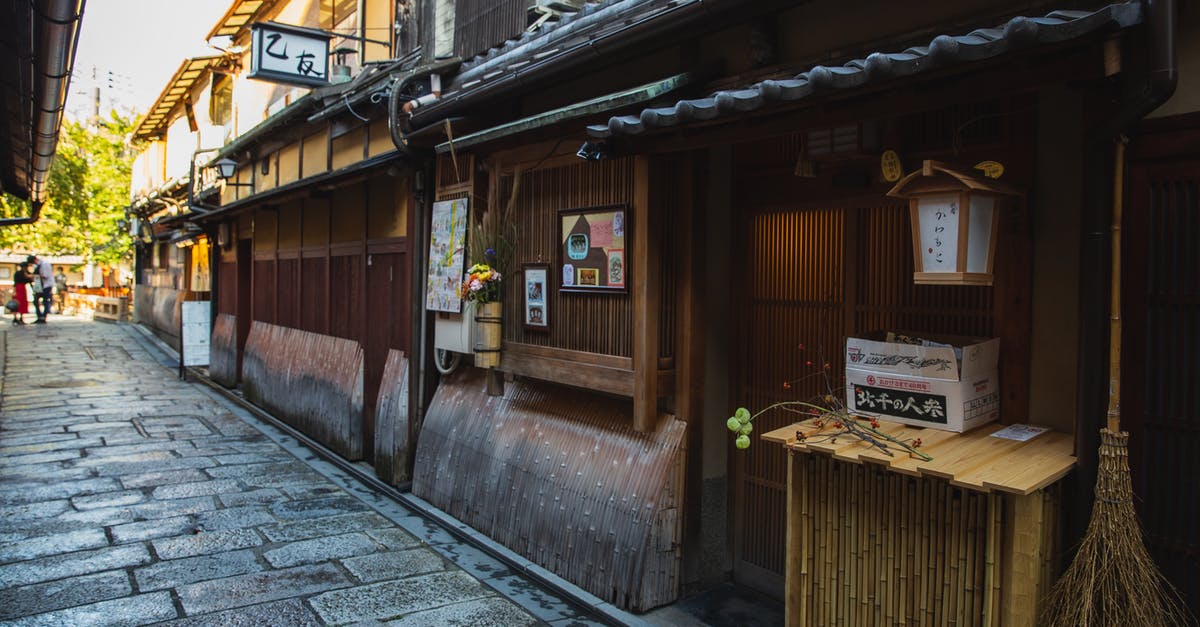 South East Asia - double entry without visa - Exterior of aged wooden houses with hieroglyphs located along narrow passage made of paving stone