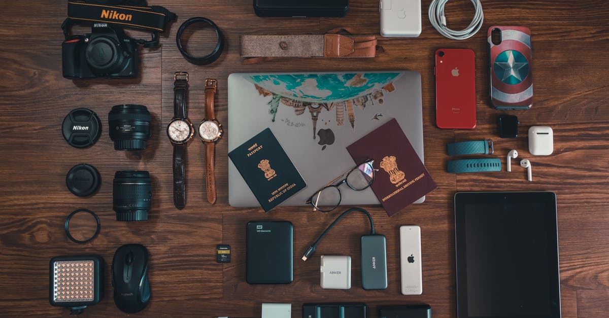 Souvenir stamps on old/cancelled passport - Passports, Camera, Battery Charger, Watches, and Cables on Brown Wooden Surface