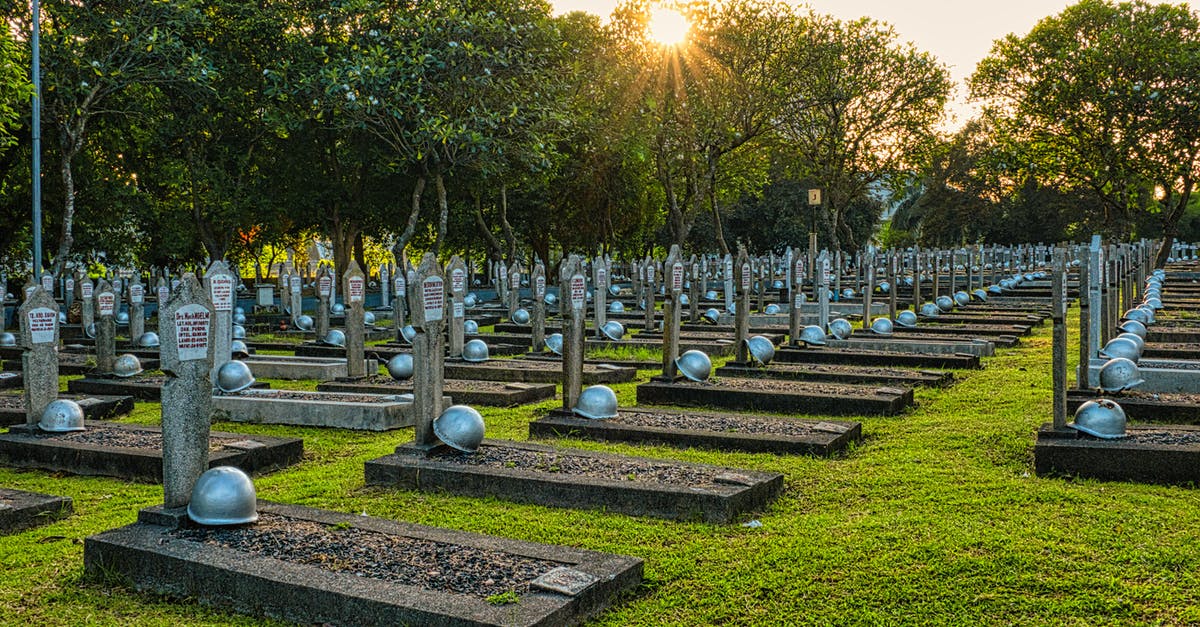 St. Angelo's fort tomb stone - Rows of tombstones with military helmets located on grassy ground near tall lush green trees in heroes cemetery in Kalibata