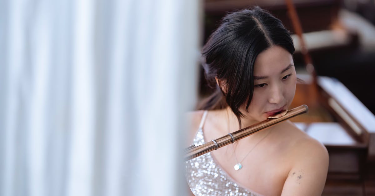 Standards of dress for a classical concert in the Czech Republic - Asian woman playing flute during rehearsal in studio