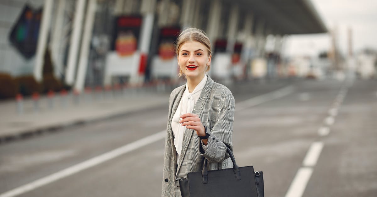 Stand-By Flights, Regardless of Destination? [duplicate] - Positive female passenger wearing formal plaid suit standing on asphalt road to airport with handbag and suitcase while smiling looking at camera during business trip