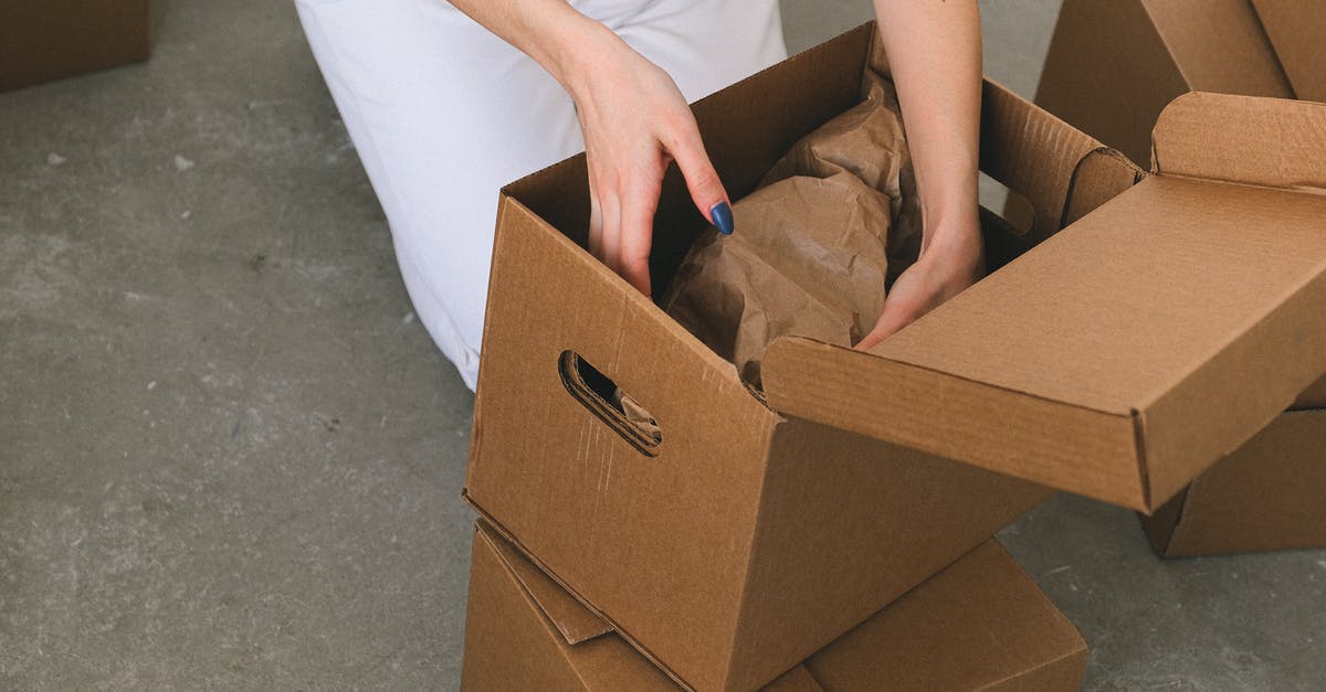 Standby shipping of my stuff from Thailand to Vietnam - Crop faceless woman packing belongings into cardboard box before relocation