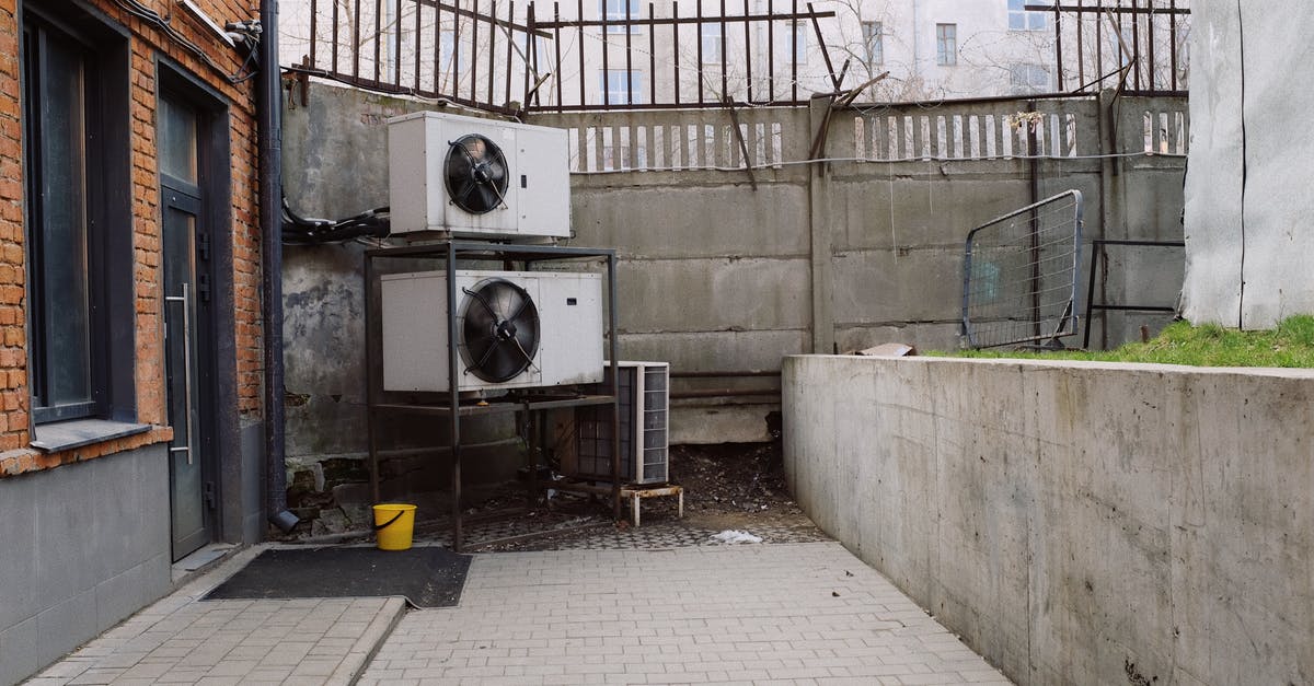 Stavropol City, surrounding area - Safety - Air conditioning system located outside concrete shabby fence with metal barrier near industrial building from bricks and glass door