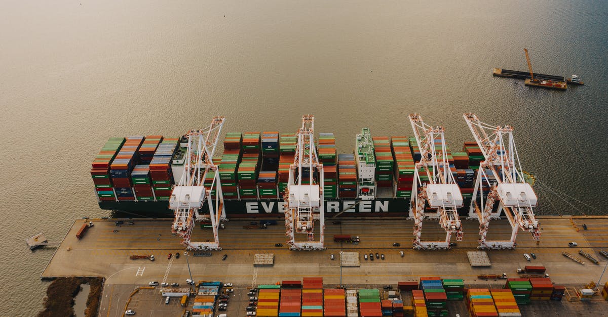 Stopping at an airport different from destination - From above of many cargo containers on ship moored on calm water of river in daytime