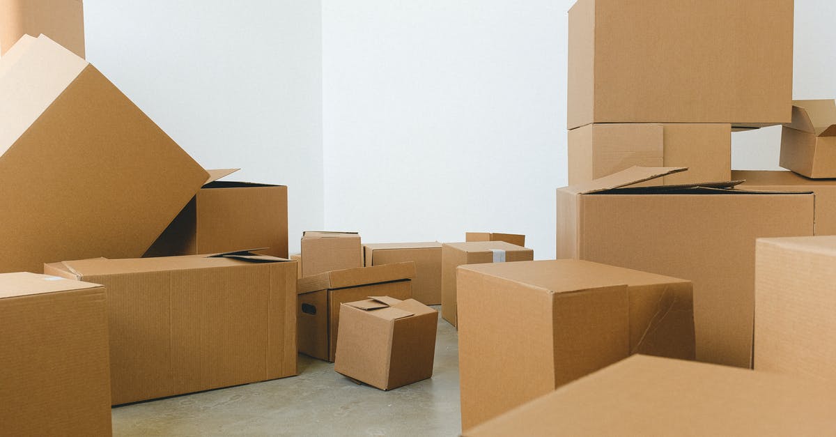 Storage that ships belongings to location [closed] - Stack of carton boxes of various shapes and sizes scattered in floor near white walls during relocation