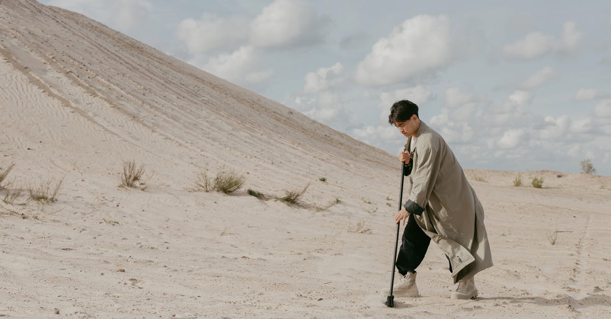 Strange landing interview at LGW for an EEA national - Man Standing On A Sandy Desert Sweeping With A Broom