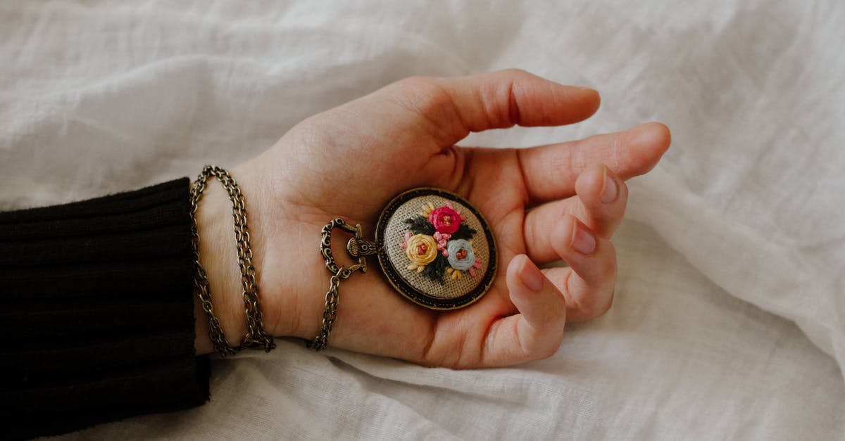 sturdy, metallic chess clock as carry-on baggage - Top view of crop anonymous female with vintage chain watch on hand on white fabric