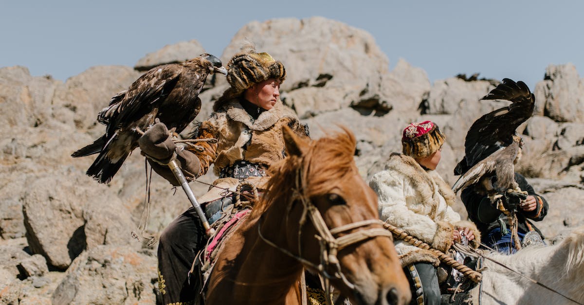 Sustainable hunting in South-East Asia - Mongolian horsemen with eagles riding on rocky terrain