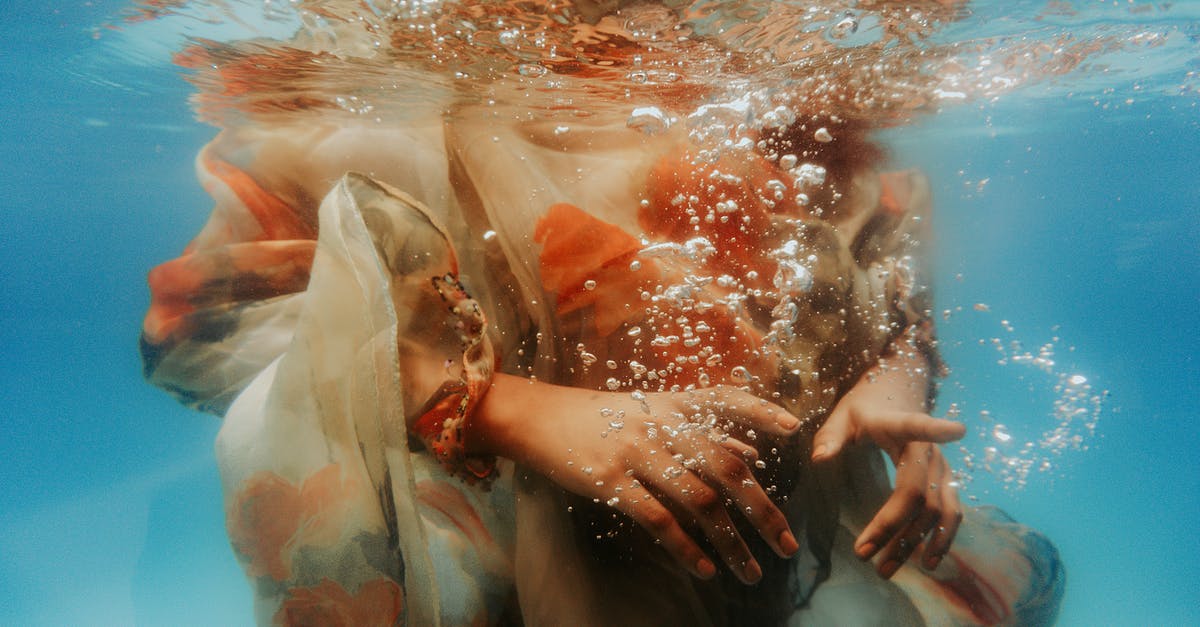 Swimming pool dressing code in Luxembourg - Underwater shot of crop unrecognizable female wearing summer dress diving into clean seawater