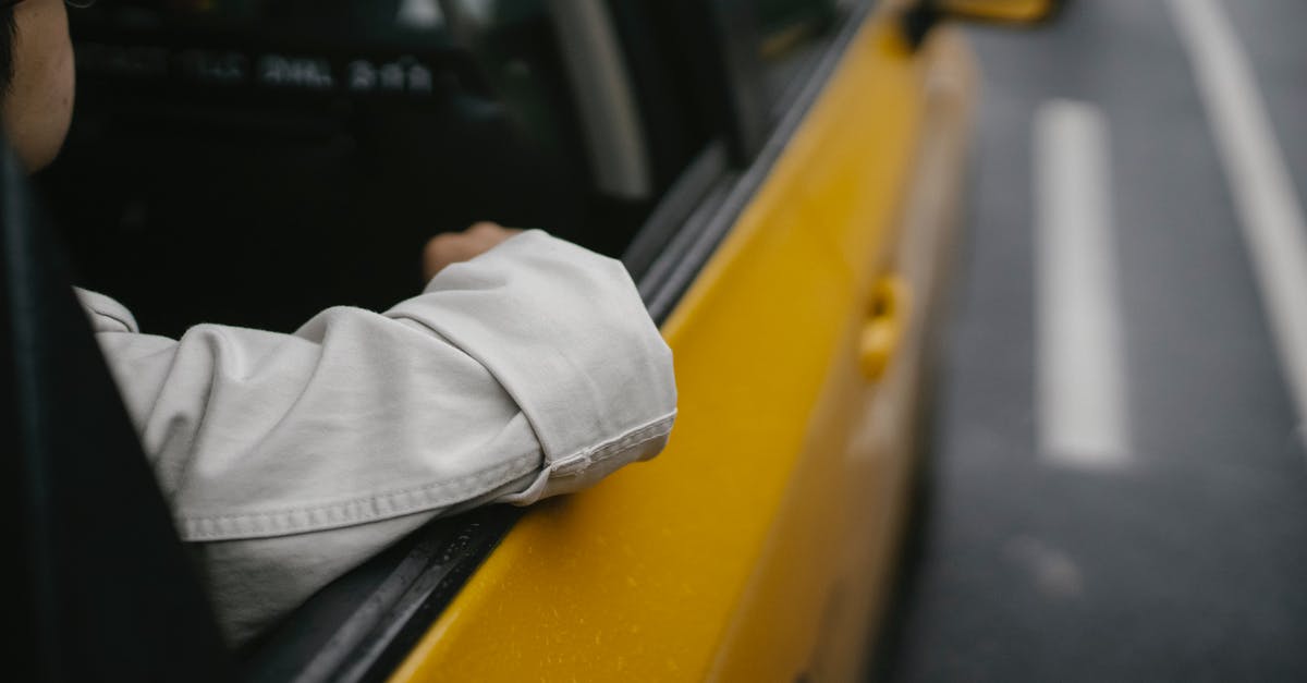 Taking a taxi in Argentina with a newborn: is the toddlers seat necessary? - Unrecognizable man in shirt and eyeglasses sitting in yellow cab while looking away in soft daylight