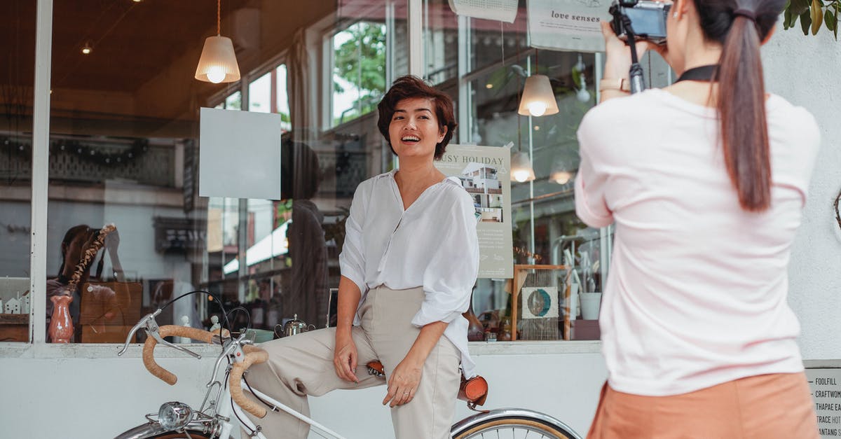 Taking my bike on overland transport - Unrecognizable woman taking photo of happy ethnic girlfriend on camera