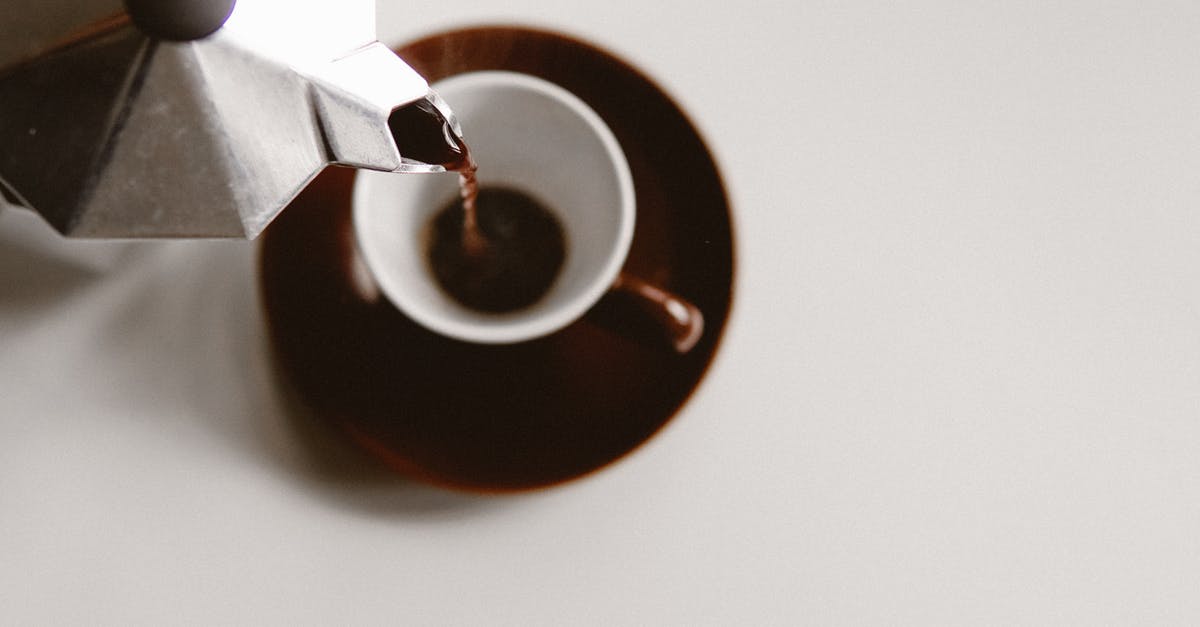 Tasting typical Icelandic cuisine in Reykjavík - From above of geyser coffee maker pouring freshly brewed beverage into ceramic cup placed on white table