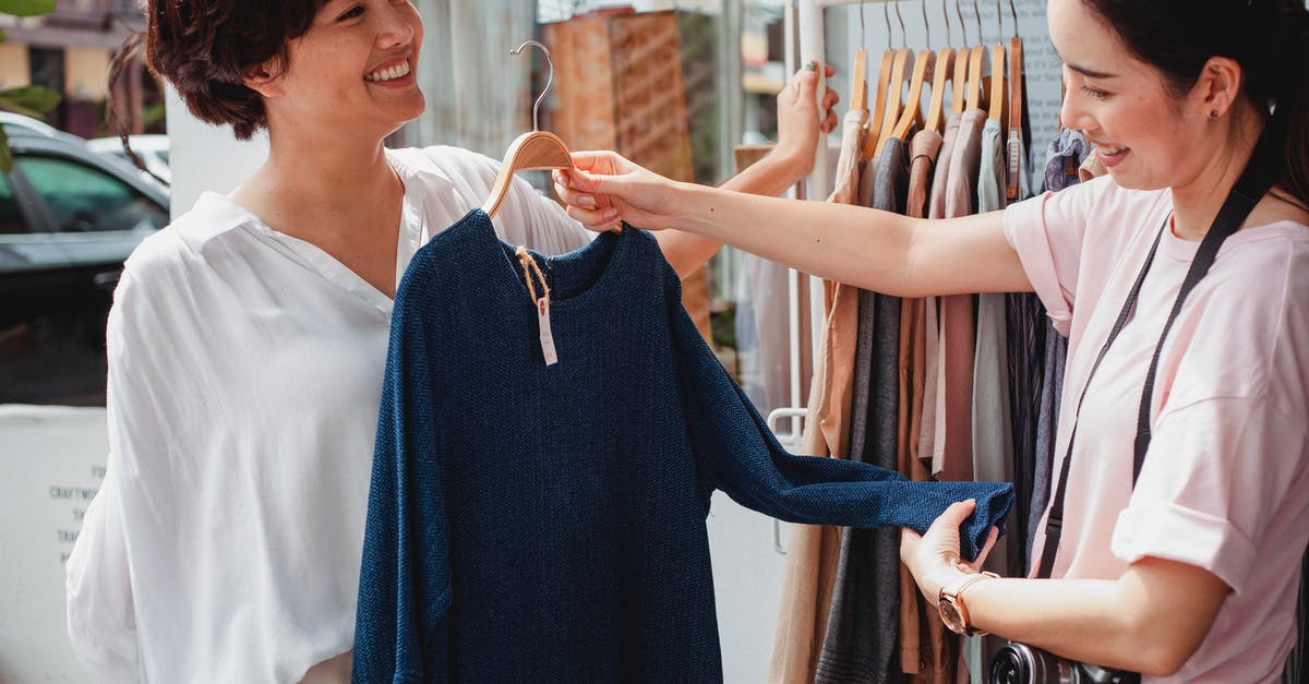 Tax-free shopping in Faroe Islands - Crop Asian buyer with girlfriend selecting clothes in street shop