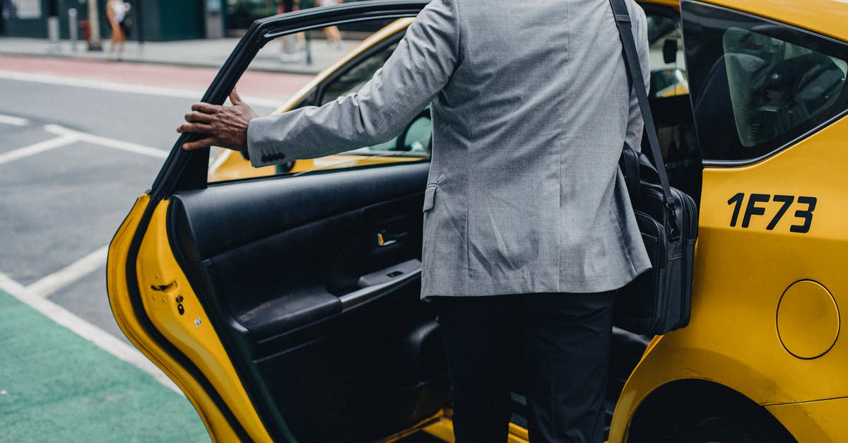 Taxi from Walthamstow Central - Back view crop unrecognizable African American male in formal outfit opening taxi door on modern city street