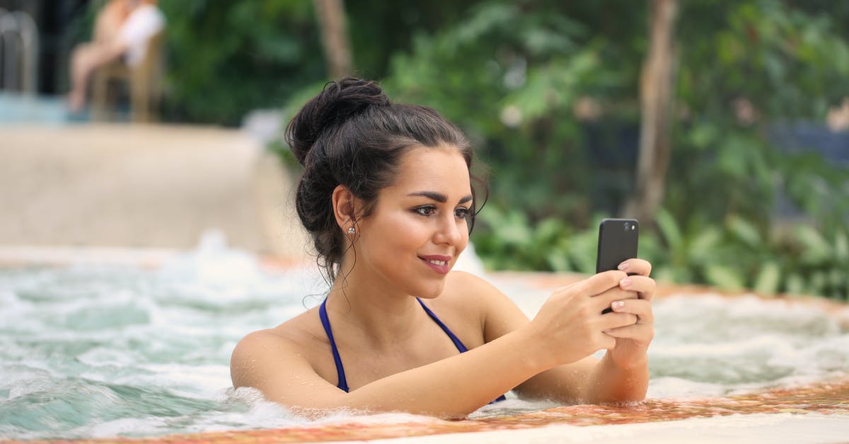 Texting someone who is out of the country? - Photo of a Woman in Jacuzzi Using Smartphone