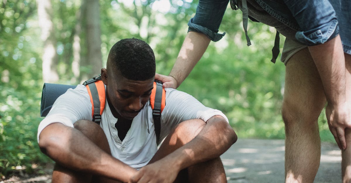 The most difficult countries to travel in? - Unhappy black hiker sitting on ground in forest