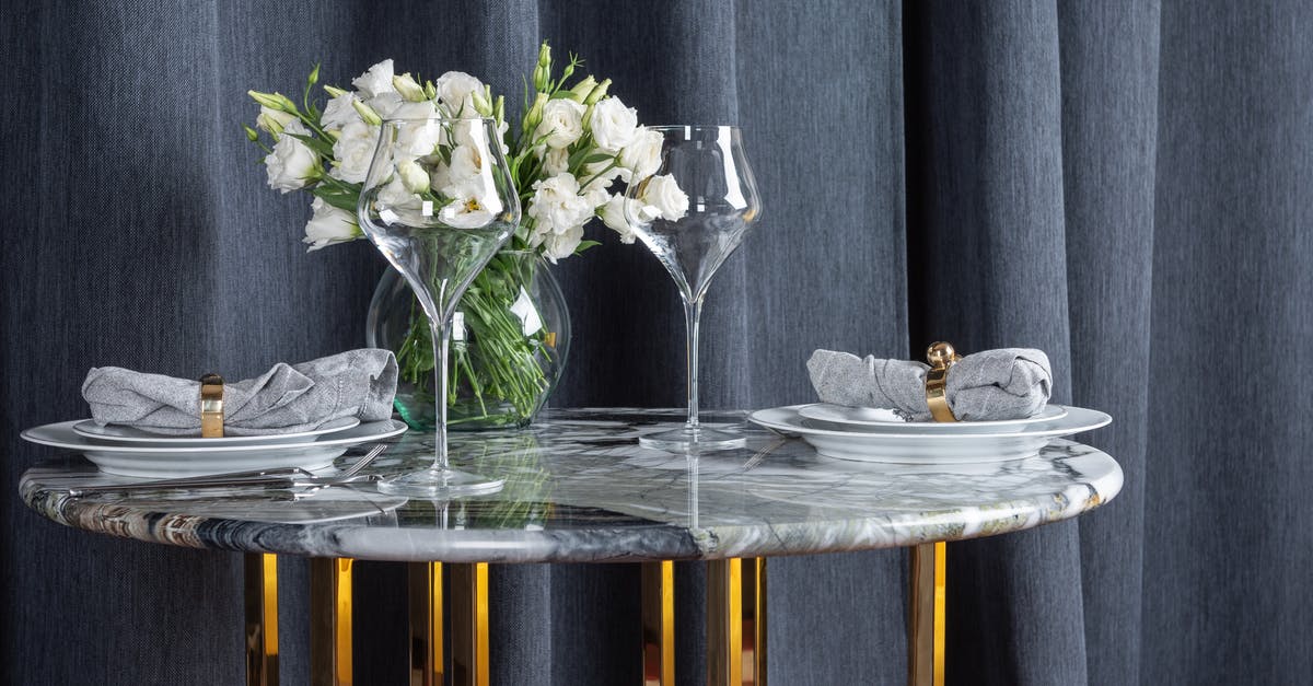 The purpose of glass goblets with coins in Italian cafes - Glasses and plates arranged with bunch of flowers in vase on marble table