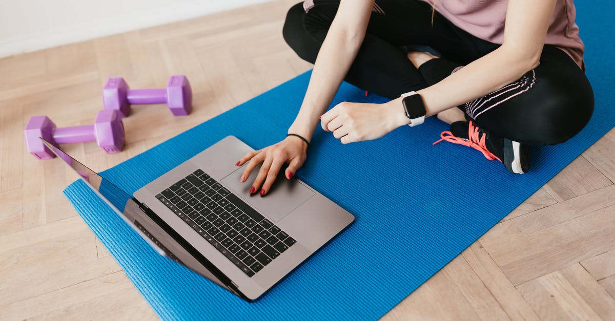 Ticket for Universal Studios LA - Online or Physical - Crop female in sportswear sitting on blue yoga mat on floor and surfing internet on laptop