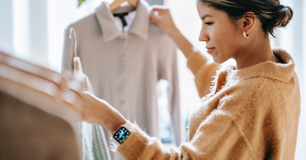 Time for Visa collection after the decision - Crop focused ethnic female in casual clothes choosing apparel while standing near rack in boutique