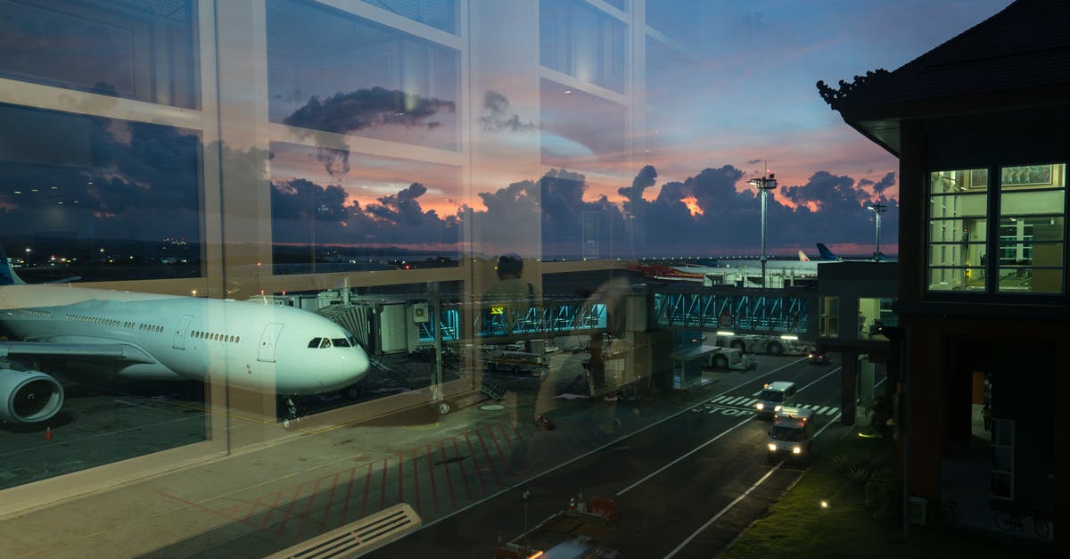 Time needed for transfer in Newark (US airport), domestic to international - Through glass modern aircraft parked near airbridge in contemporary airport against picturesque dusk sky Time needed for transfer in Newark (US airport), domestic to international - Through glass modern aircraft parked near airbridge in contemporary airport against picturesque dusk sky