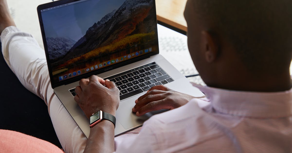 Time taken for customs check in Brisbane Australia - Black man with smart watch using touchpad of laptop