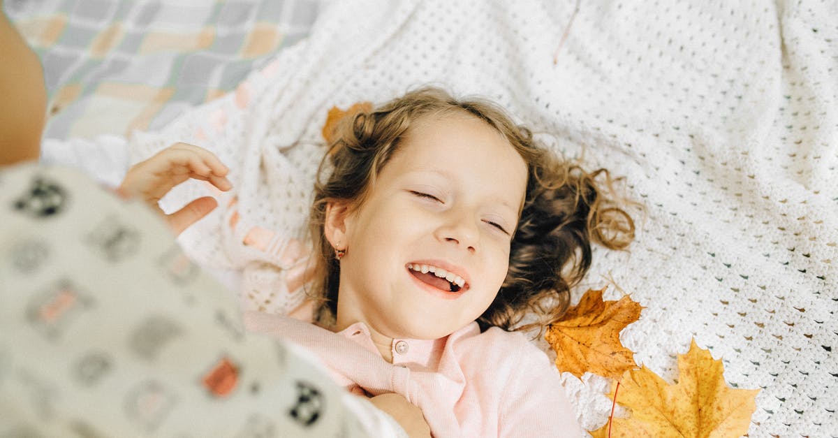 Timing of yellow fever vaccination - Girl in Pink Long Sleeve Shirt Lying on White and Brown Floral Textile