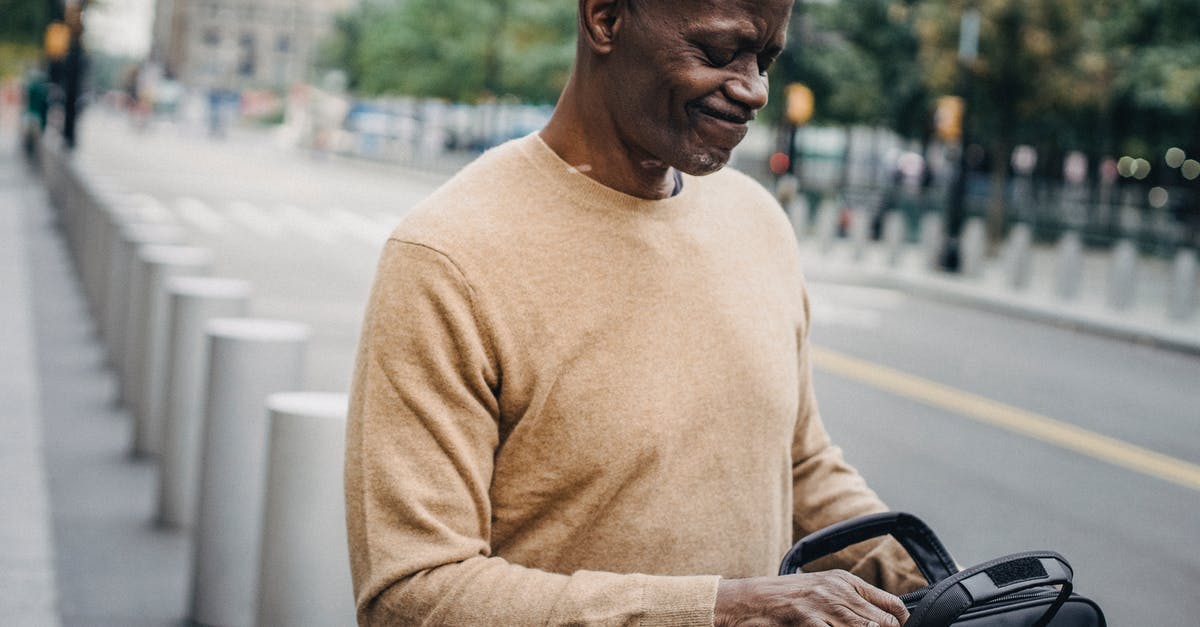 Tips to avoid forgetting a bag - Frowning black businessman with personal case looking inside and grimacing while standing in street