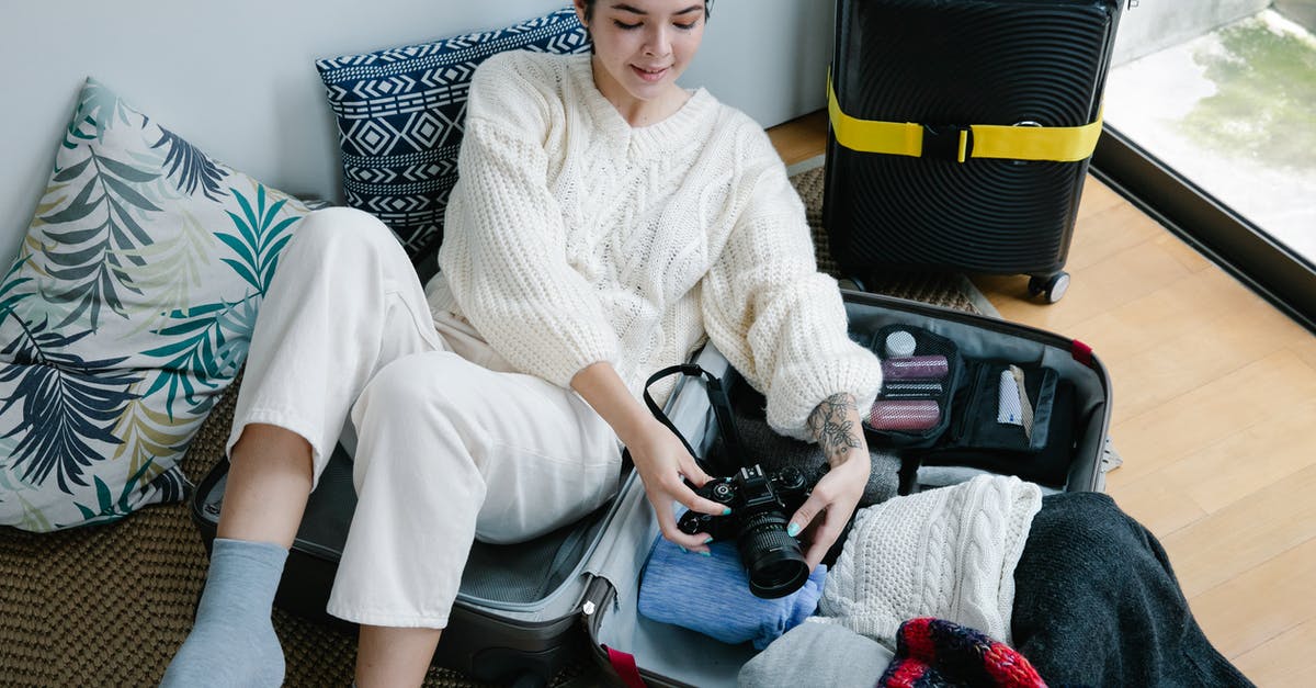 Tolerated amount of weight exceeding upper limit for hold luggage - Woman Sitting on Luggage Holding Black Camera