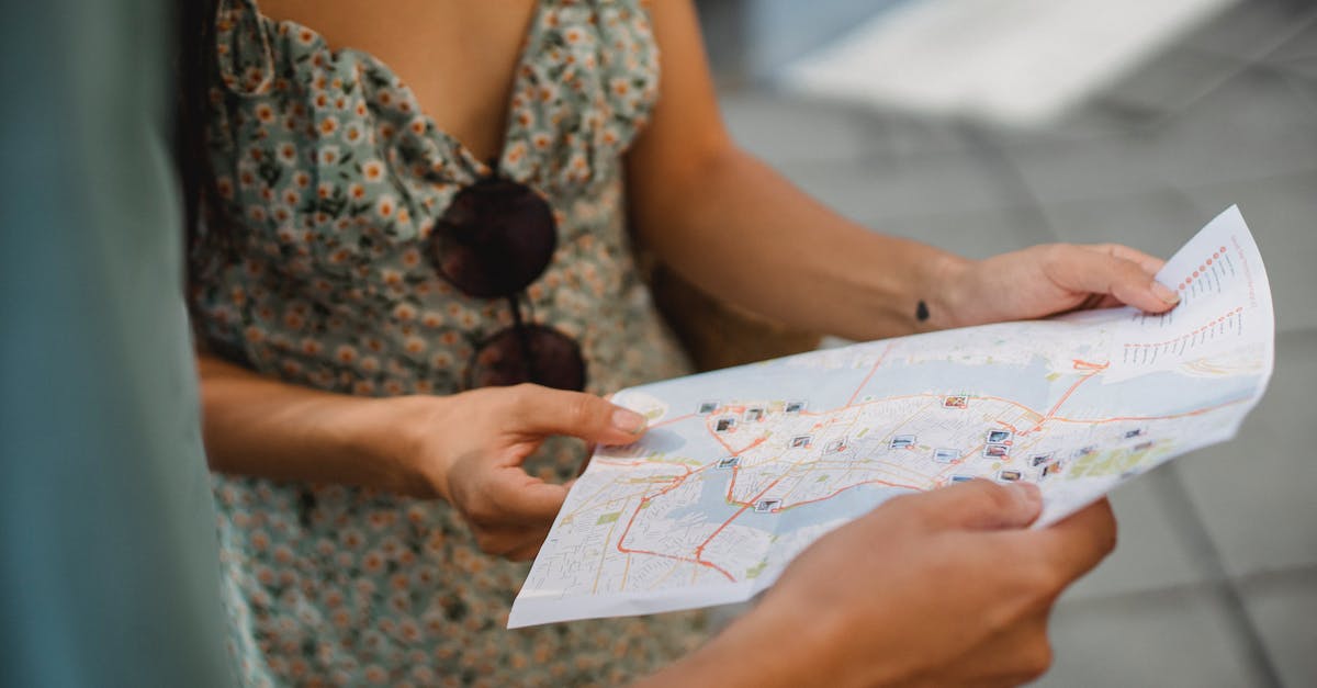 Tourist guide in Philippines - Crop anonymous couple travelers in summer clothes checking location in paper map while walking in unknown city