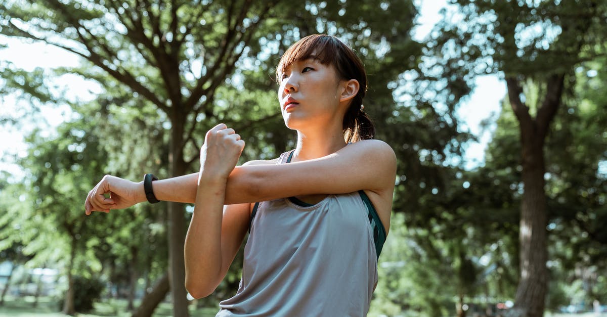 Train from Istanbul To Izmit and back - From below of serious Asian female athlete in sportswear stretching arms and back muscles while doing exercises in park