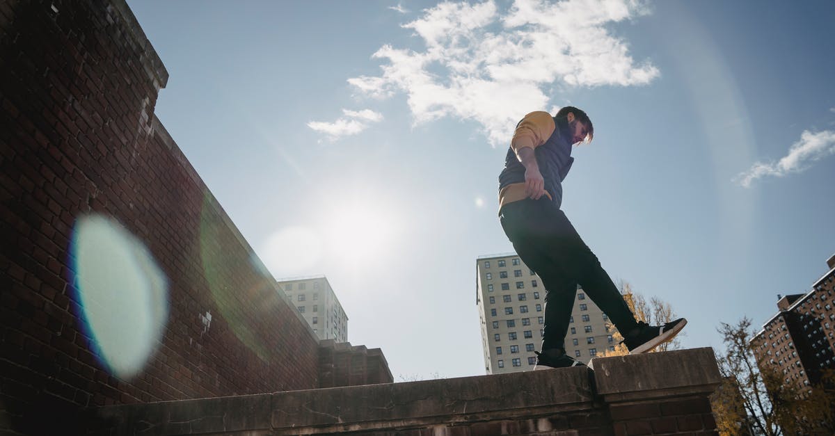 Train from Nice to Moscow / Border Controls - From below full body side view of energetic male standing on roof of brick construction against blue sky on street