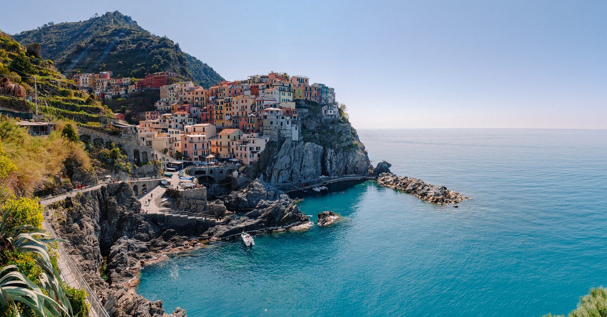 Trains in the Cinque Terre - Breathtaking scenery of historic colorful buildings of famous coastal Manarola town located on stony hill in front of turquoise sea on sunny day