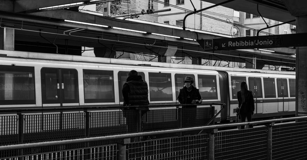 Transfer from Intercity train to Warsaw Chopin - Black and white of citizens on railway station walking on platform near public train against modern buildings in city center