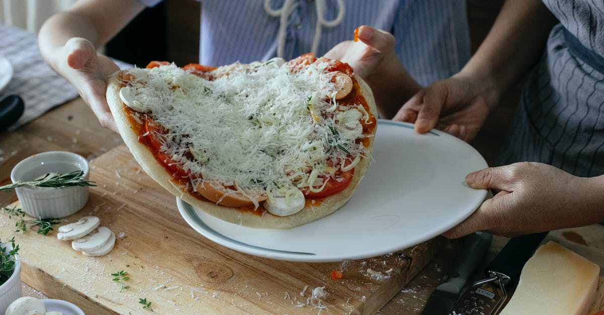 Transfer time from JFK to EWR - High angle of crop anonymous women transferring uncooked yummy homemade pizza on platter during preparation to baking in kitchen