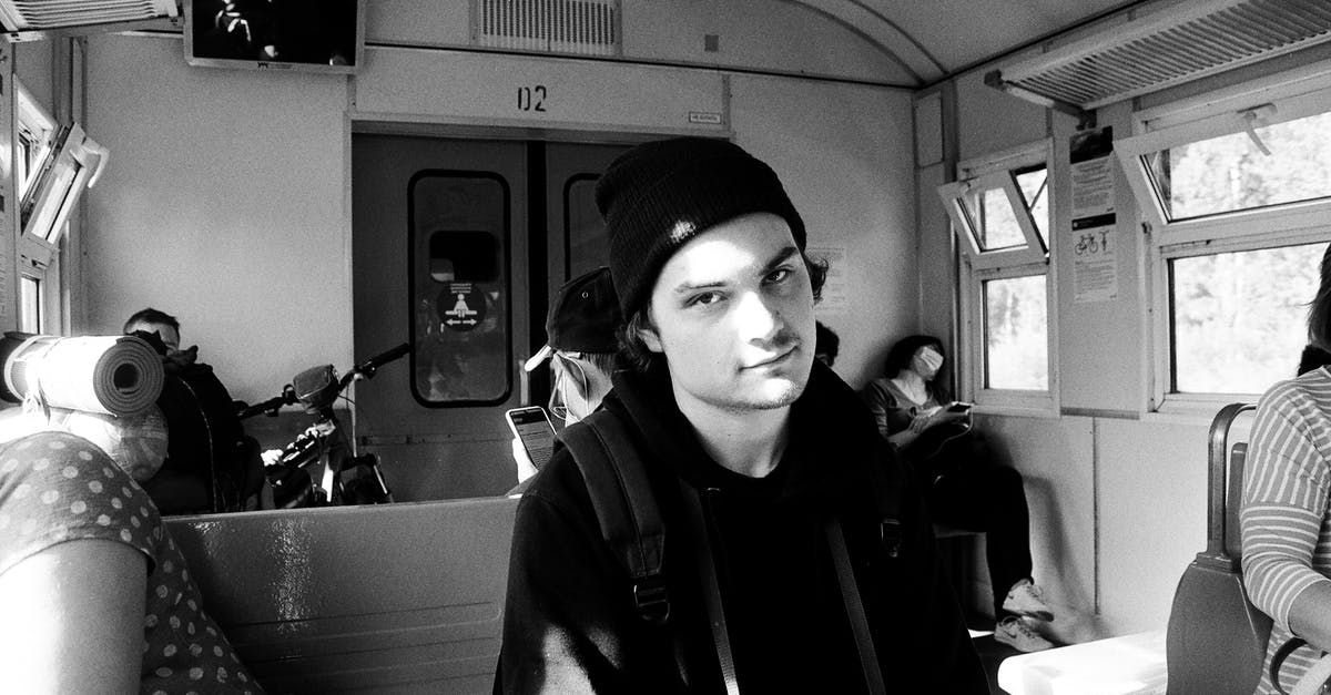 Transit counted as Schengen days? - Black and white of young man in black clothes siting on seat in train in sunny day