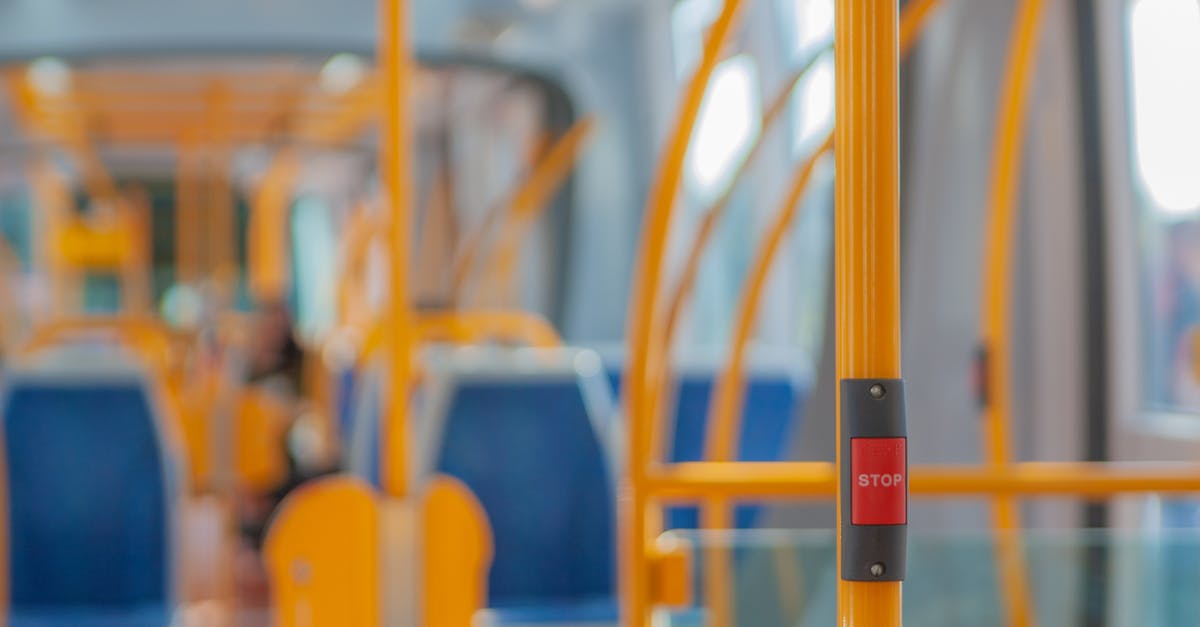 Transit in Curaçao - Red stop button on yellow handrail in modern empty public bus during daytime