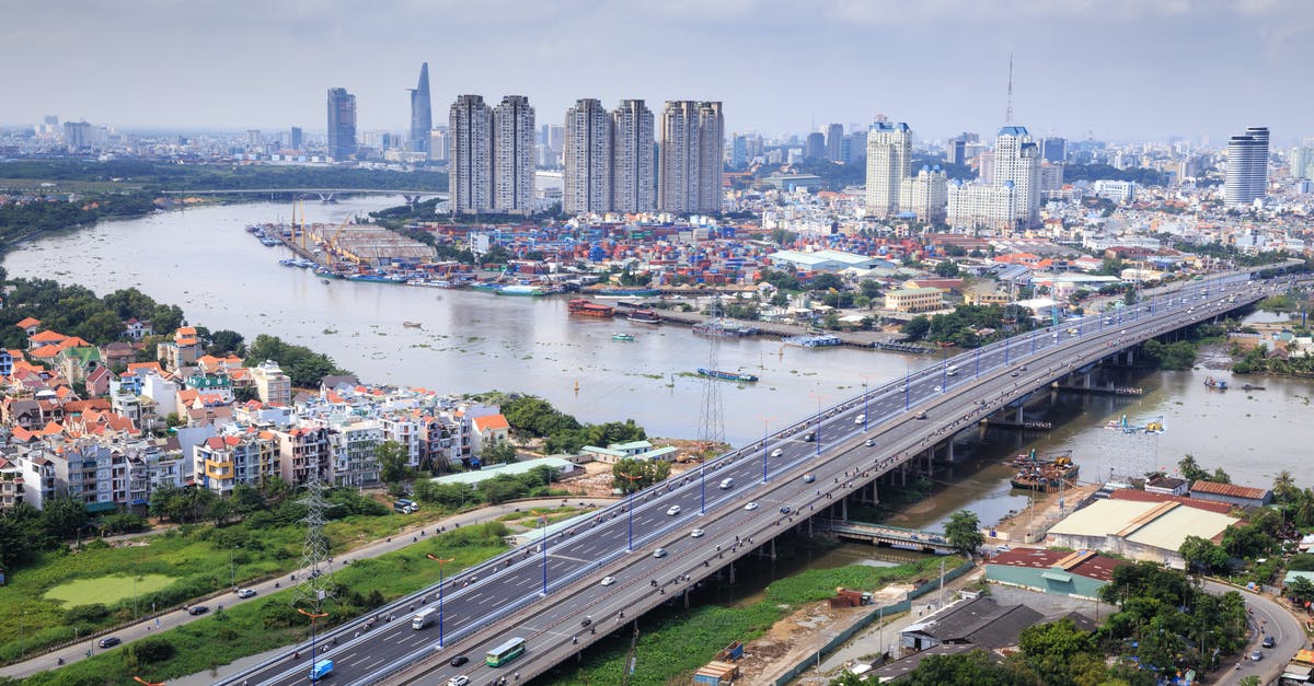 Transit in Ho Chi Minh City [closed] - Different Vehicles on Road Near High-rise Buildings Showing Bridge and Sea