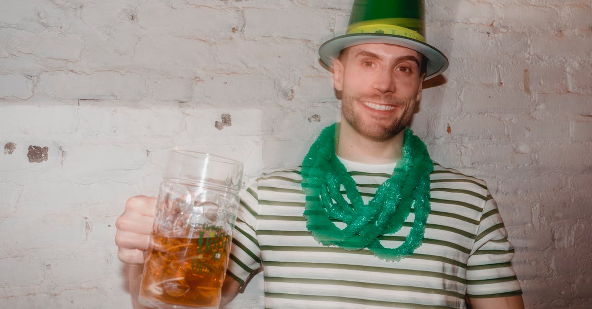 Transit through UK with Irish visa - Through glass wall view of smiling male in shamrock hat looking at camera with jar of beer during Feast of Saint Patrick