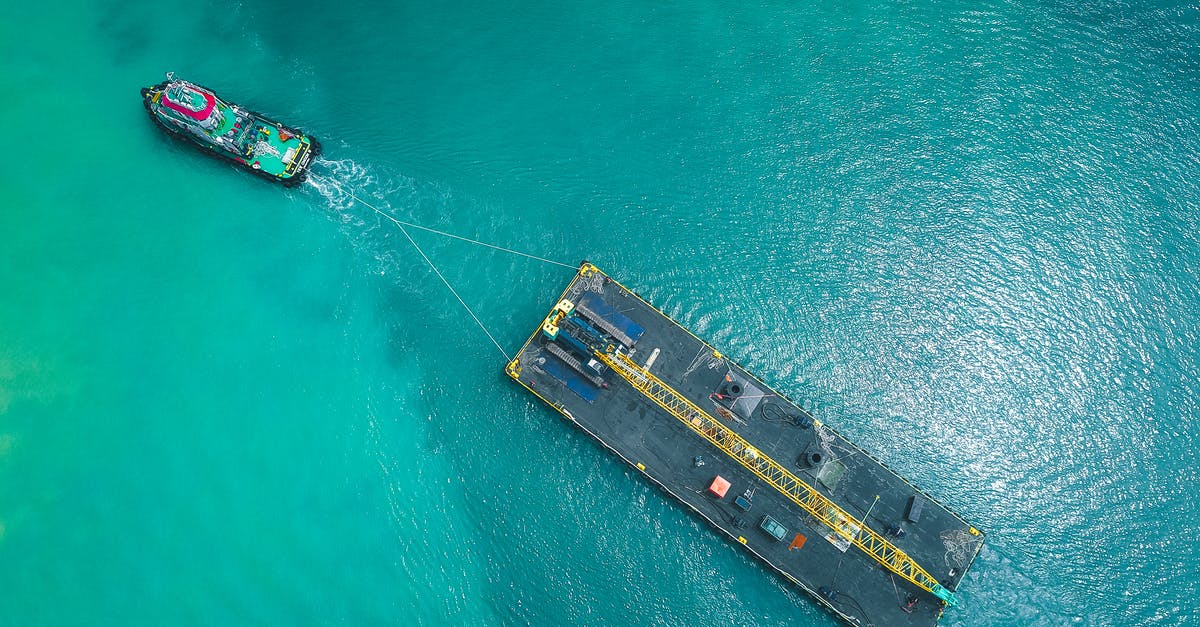 Transit Visa disembarking from cruise ship? - Aerial view of modern vessel floating on rippling blue seawater and pulling big platform
