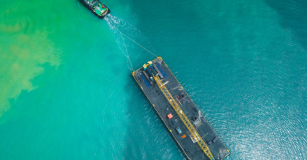 Transit Visa disembarking from cruise ship? - Aerial view of modern powerful motorboat floating on azure seawater and transporting big platform with crane