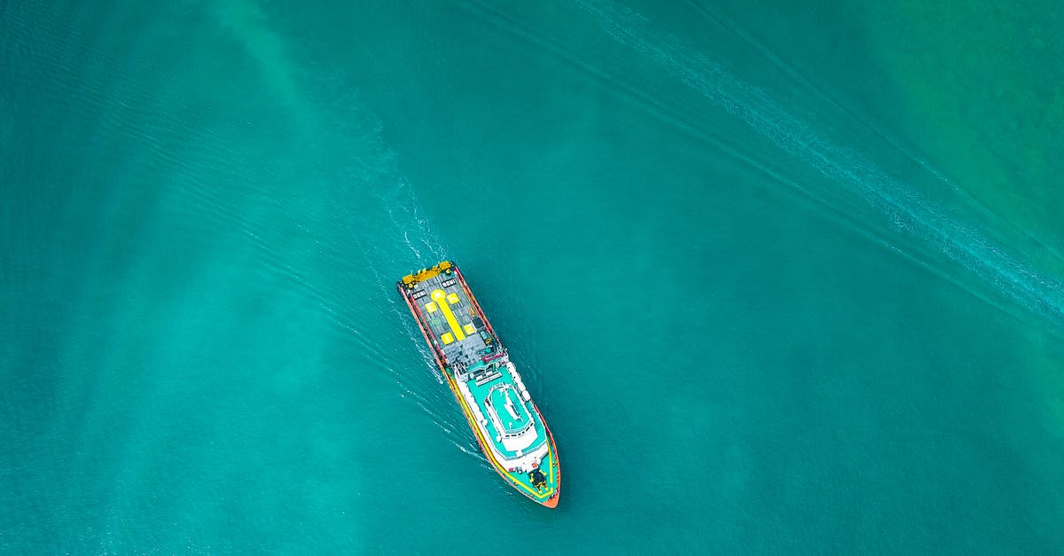 Transit Visa disembarking from cruise ship? - Aerial view of contemporary industrial boat floating along turquoise rippling ocean on clear day