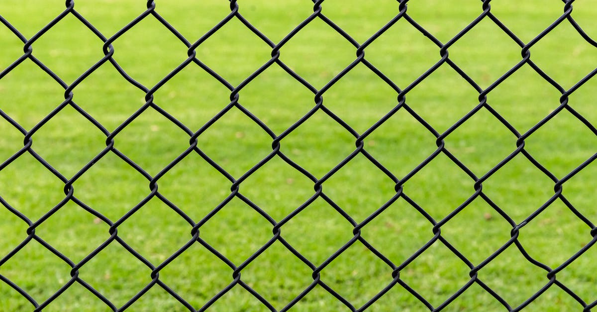 Transiting through Canada without going through border control [duplicate] - Full frame background of fence with chain link net on blurred green meadow